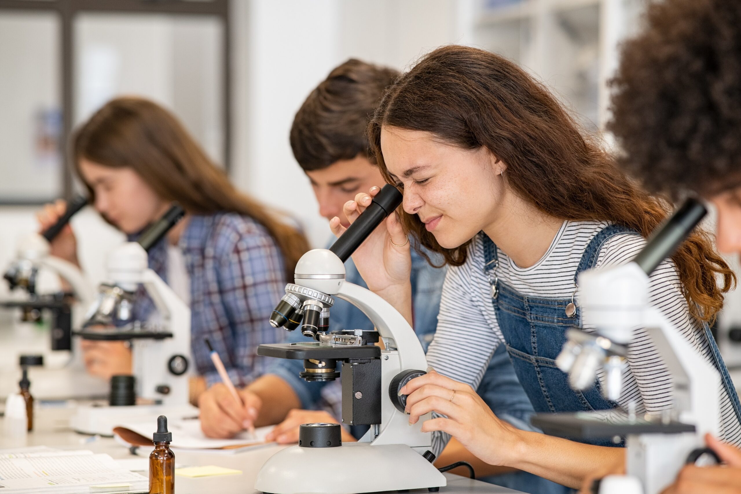 Studenten werken met microscopen tijdens praktijkgericht onderwijs in een moderne leer- en onderzoeksomgeving.